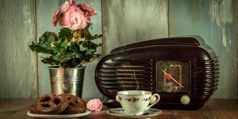 Vintage radio set on a table with a cup of tea beside and some flowers