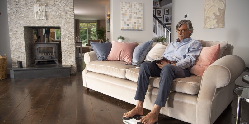 Man sat on sofa using Revitive device